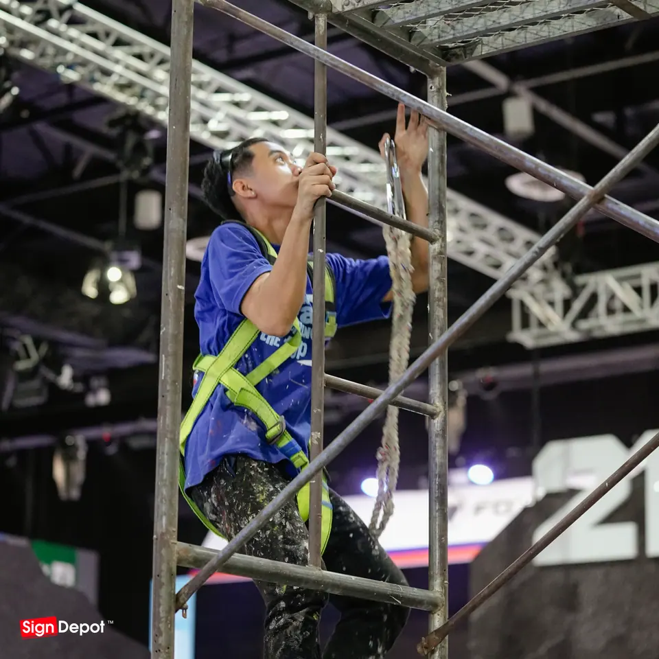 An installer in a harness works on the scaffold