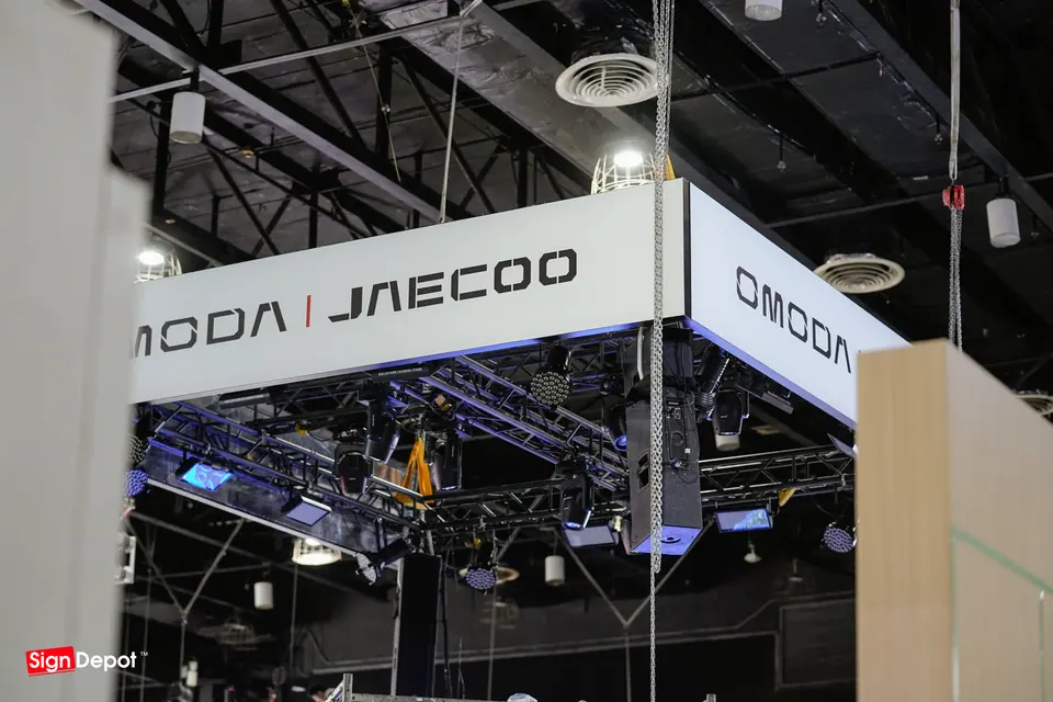 The Omoda Jaecoo header sign rigged above the booth
