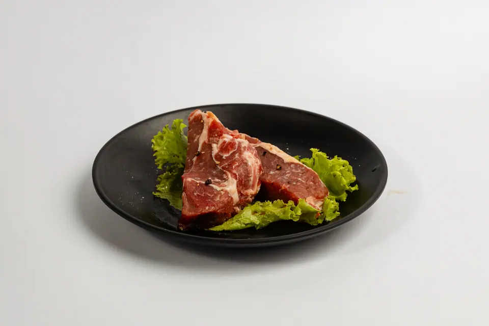 A marbled beef cut on lettuce in a black bowl