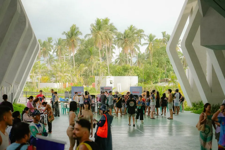 Participants register under the canopy by the palm trees