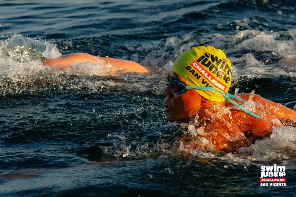 A swimmer in a yellow cap powers through the waves