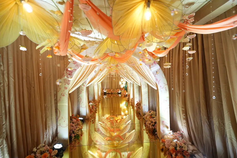A gold and blush draped aisle lit from above