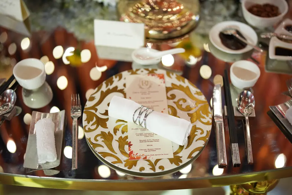 A gold charger, menu card and glassware at a place setting