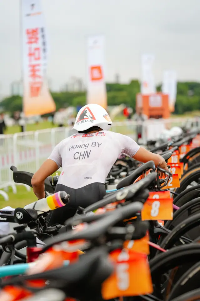 An athlete racks his bike in the transition area among numbered race bikes