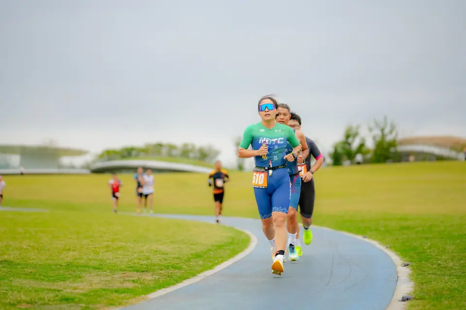 Two runners on the run course across a wide green park