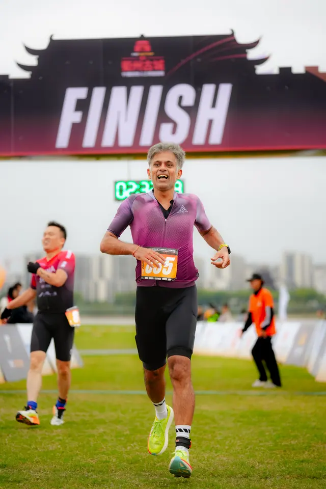 A runner in a purple suit crosses under the FINISH arch
