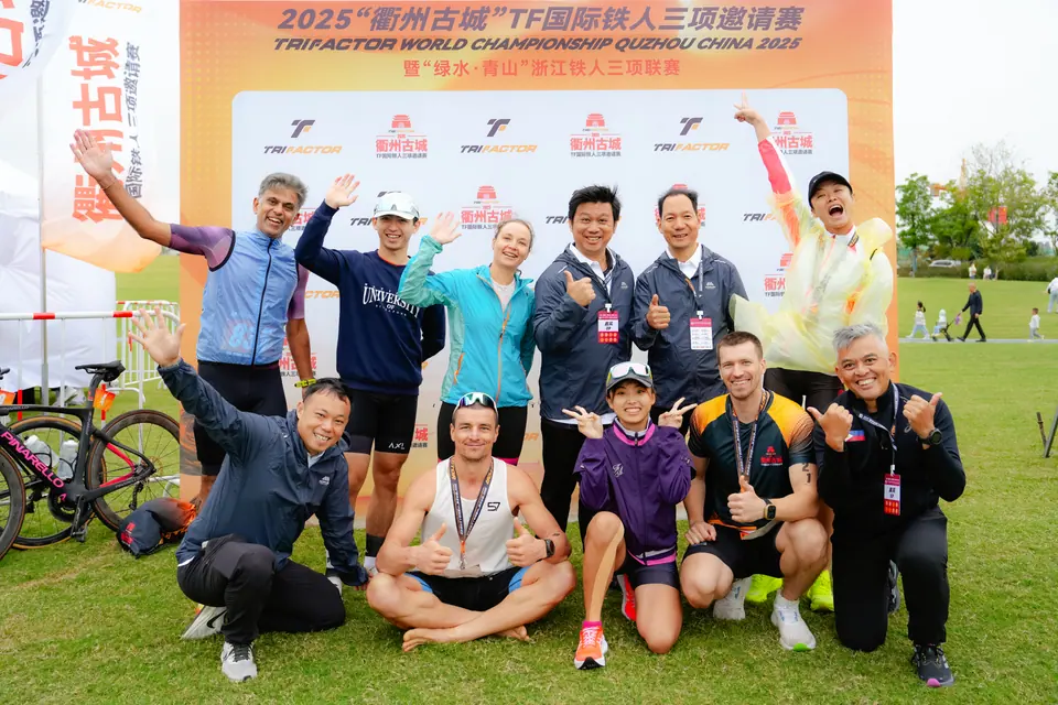 Athletes and officials pose in front of the Trifactor World Championship Quzhou backdrop